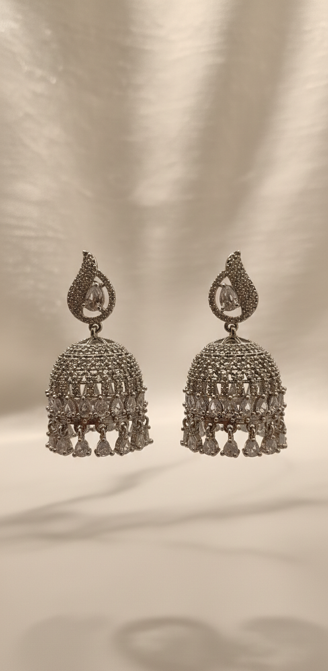 Pair of ornate silver earrings on a beige background