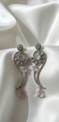 Elegant silver earrings with pink gemstones on a white fabric background