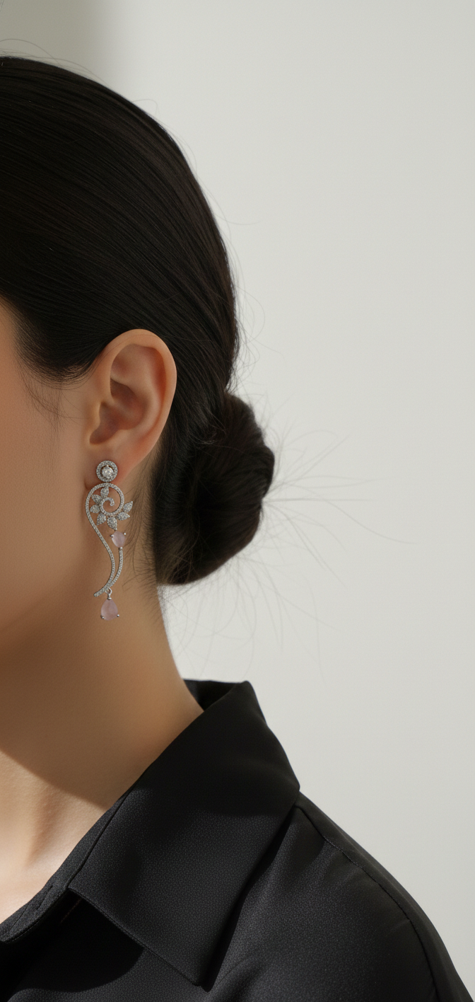 Close-up of a person wearing elegant silver earrings against a neutral background
