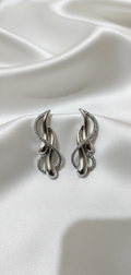 Pair of silver earrings on a white satin background