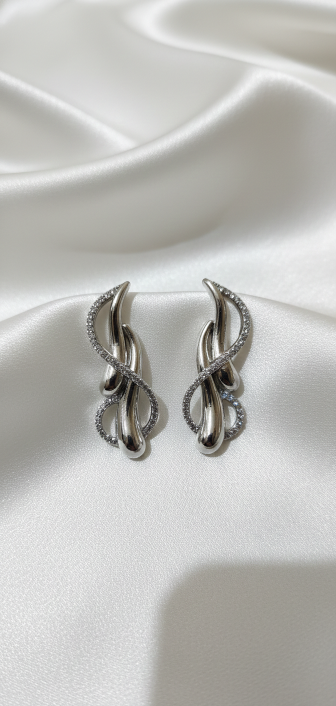Pair of silver earrings on a white satin background