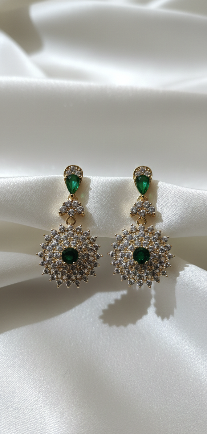 Pair of earrings with green gemstones on a white fabric background