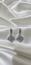 Pair of diamond earrings on a satin surface