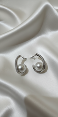 Pair of silver hoop earrings with pearls on a satin surface