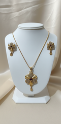Gold necklace and earrings on a white mannequin bust with a neutral background