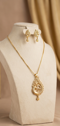 Gold necklace and earrings set on a beige stand with a beige background