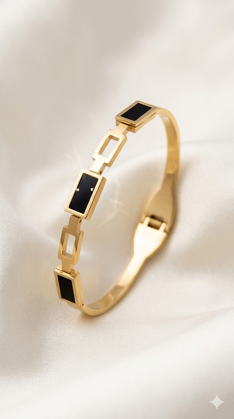 Gold bracelet with black square stones on a light background