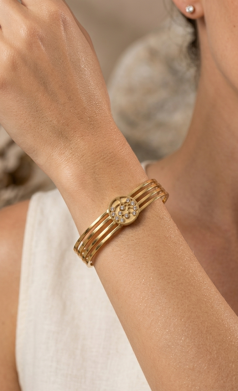 Gold bracelet on a wrist with a neutral background