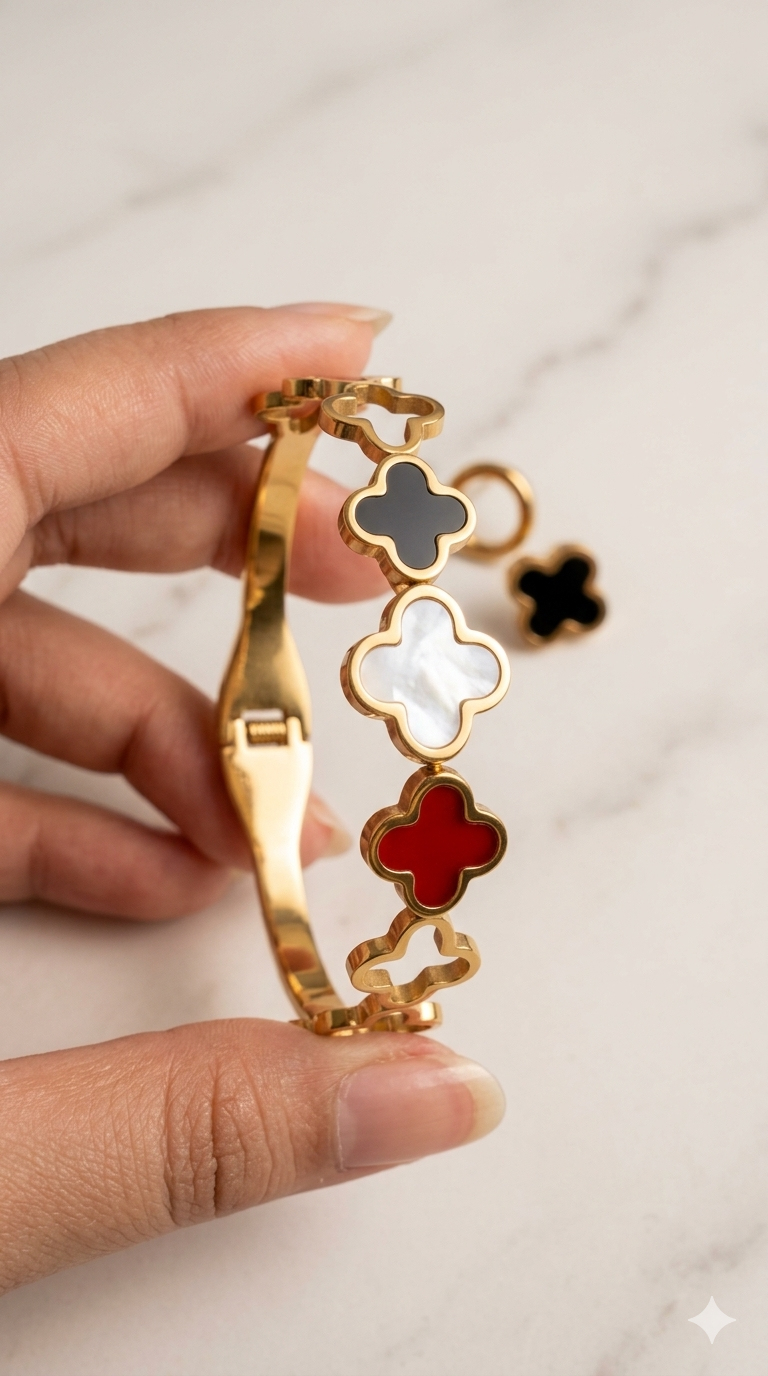 Gold bracelet with clover-shaped charms held by a hand on a light background