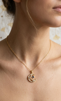 Gold necklace with a pendant worn by a person against a neutral background