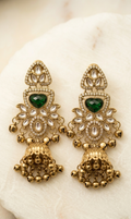 Pair of gold earrings with green gemstones on a white stone surface
