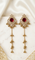 Gold earrings with red gemstones on a white fabric background