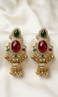 Pair of gold earrings with red and green gemstones on a white background