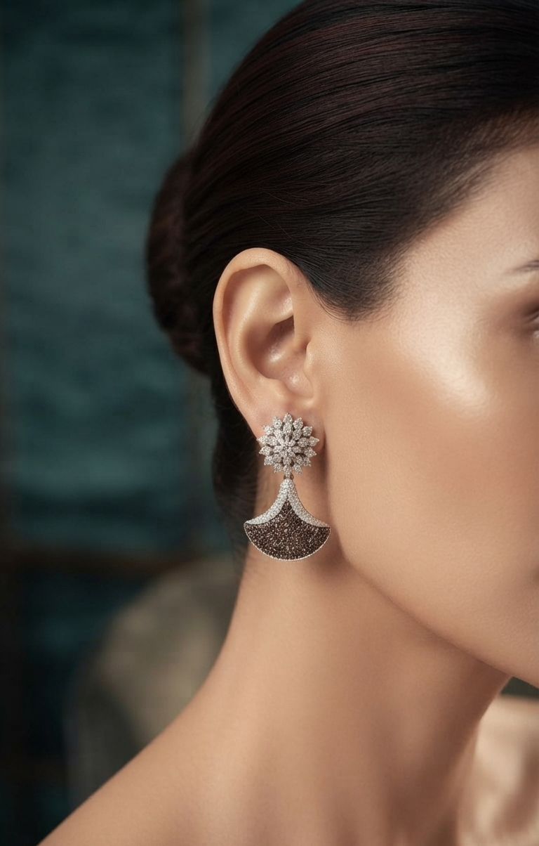A close-up side profile of a woman wearing a dramatic silver-toned dangle earring with a floral cluster top and a fan-shaped lower section set with dark stones.