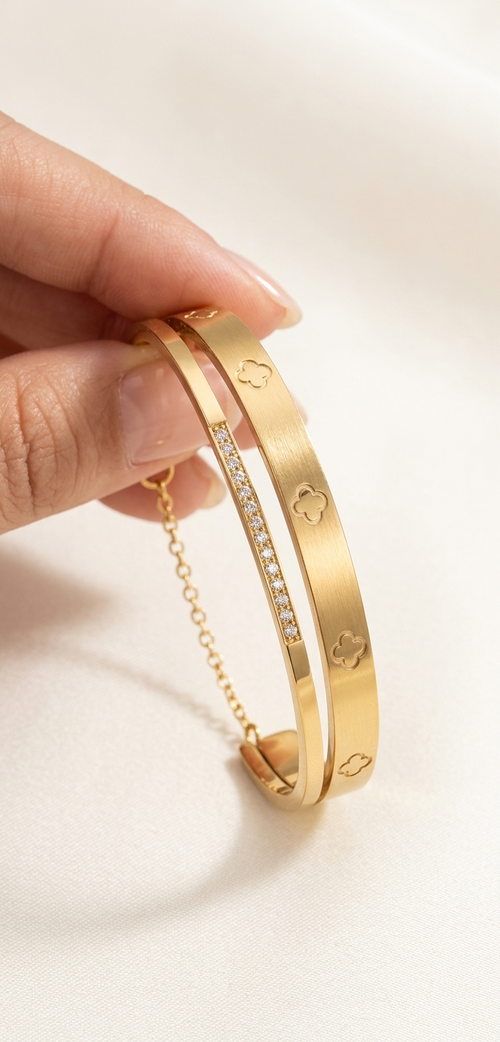 Gold bracelet with heart designs held by a hand on a light background