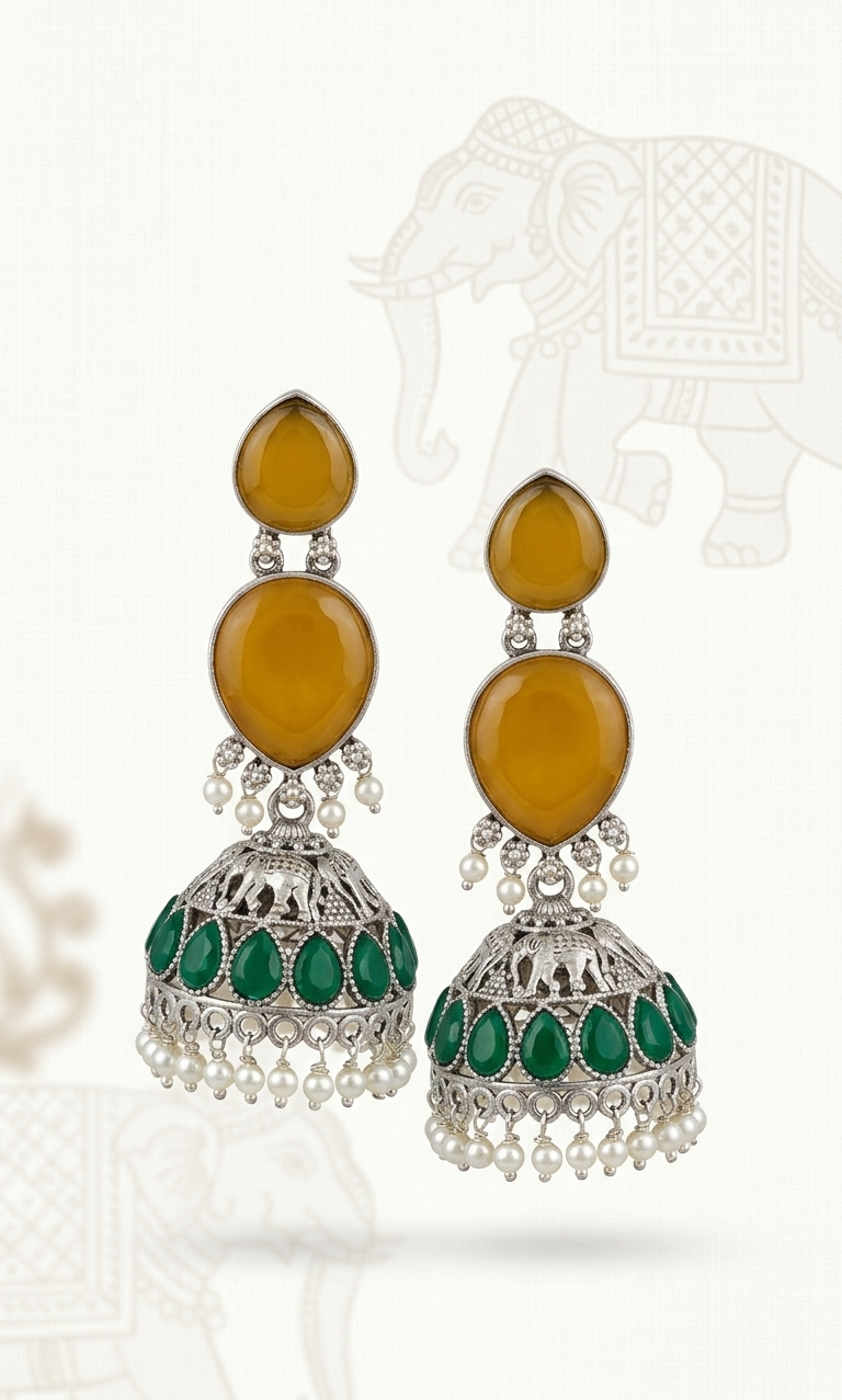 Pair of ornate earrings with amber and green stones on a white background