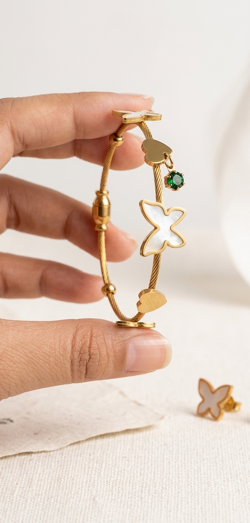 Gold bracelet with star and heart designs held by a hand on a white background