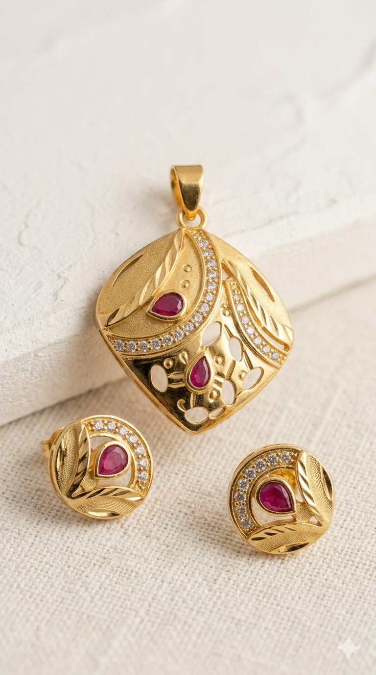 Gold pendant and earrings with red gemstones on a textured beige surface