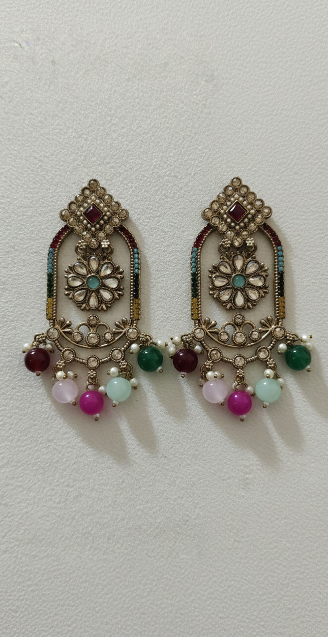 Pair of ornate earrings with colorful beads on a light gray background