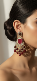 Close-up of a woman wearing a pair of ornate earrings with red gemstones.