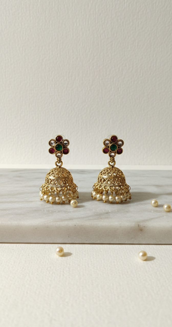 Gold earrings with green gemstones on a white surface