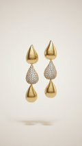 Gold earrings with teardrop-shaped designs on a beige background