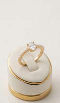 Gold ring with a diamond on a matching gold and beige ring box