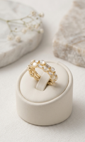 Gold ring with pearls on a white jewelry box against a light background