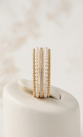 Set of pearl and gold rings on a white surface with a soft beige background