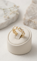 Gold ring with pearls on a white jewelry box against a light background